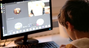 Widok chłopca patrzącego w stronę monitora. Na monitorze rozmazany widok z lekcji online