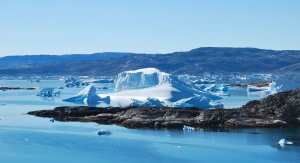 Fotografia przedstawia Fiord Sermilik na wschodnim wybrzeżu Grenlandii. Na kolejnych planach woda i nagi ląd. W wodzie znajdują się większe i mniejsze fragmenty lodu