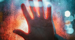 Dłoń na mokrej szybie, w nocy, oświetlona od tyłu | fot. wirestock - Freepik.com