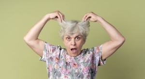 Starsza kobieta o siwych włosach podnosi włosy do góry
