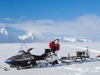 Naukowiec przewożący sprzęt badawczy na saniach śnieżnych