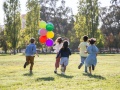 pięcioro dzieci biegnie z balonami
