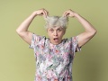 Starsza kobieta o siwych włosach podnosi włosy do góry