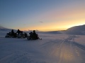Naukowcy na skuterach śnieżnych na lodowcu Hansa na tle zachodzącego słońca | fot. Michał Laska