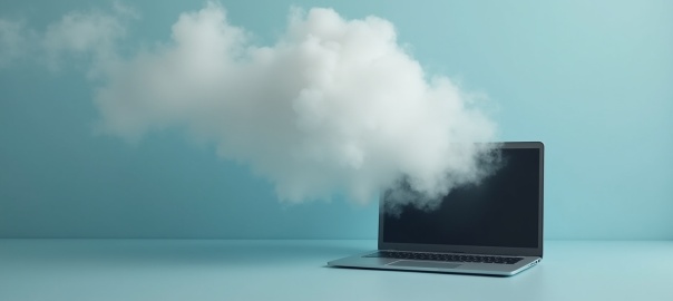 Otwarty laptom na stole, z laptopu unosi się szarobiały dym, błękitnozielonkawe tło | fot. AI